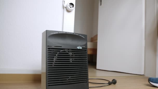 Een Man Sluit Een Elektrische Ventilator Aan Gang Kamer Verwarmen — Stockvideo