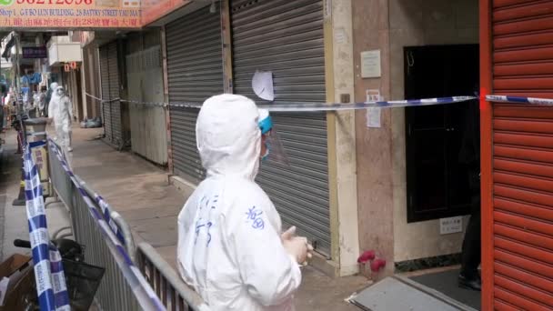 居住者は 香港でコロナウイルス Covid 変異体の流行の広がりを含むようにタップされ ロックされたエリア内の彼のアパートの建物の入り口に立っています — ストック動画