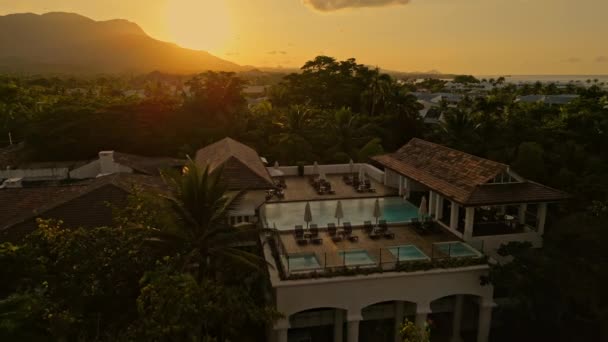 屋上プールとカーサ植民地時代のビーチと日没時のスパのパビリオン ドミニカ共和国のカリブ海沿岸にあるホテルの宿泊施設 空中プルバック — ストック動画