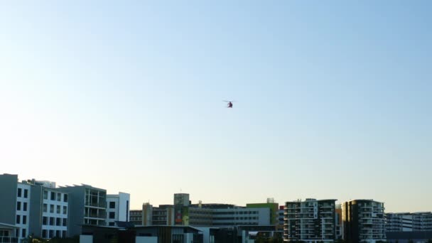 医療サービス Medevacヘリコプターがビルの上を飛んでブルースカイ 4Kスローモーションで — ストック動画