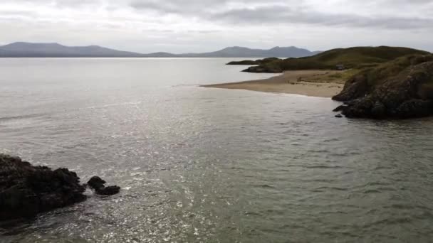 空中上升回Ynys Llanddwyn岛上的上空 沿着海滨小路与雪多尼亚山脉穿过爱尔兰海 — 图库视频影像