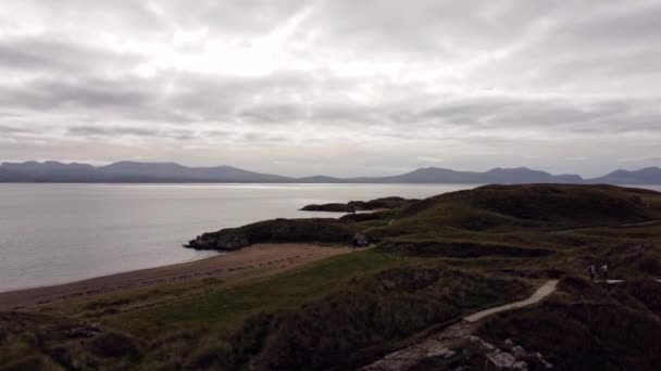 从空中俯瞰Ynys Llanddwyn岛 沿着海岸线与雪多尼亚山脉穿过爱尔兰海 — 图库视频影像