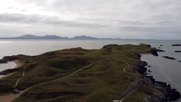 空中倒转风景Ynys Llanddwyn岛安吉丽岛海岸小径与雪多尼亚山脉穿过爱尔兰海 — 图库视频影像