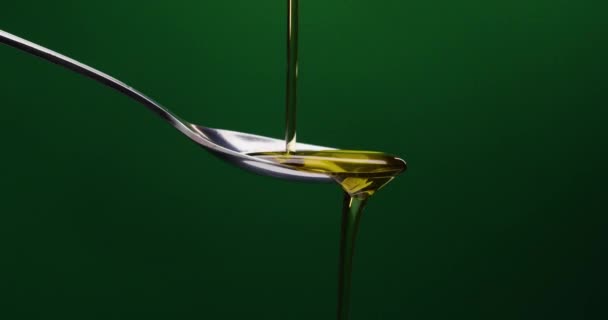 在绿色背景下倒入油的勺子静态射击 — 图库视频影像