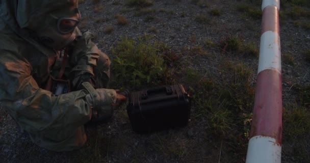 Żołnierz Kombinezonie Zabezpieczającym Sprawdza Promieniowanie Podejrzanej Teczki Przy Barierce — Wideo stockowe