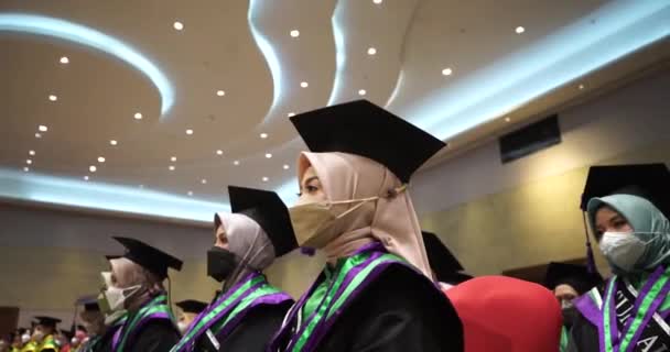 在里面听毕业典礼的毕业生 一群穿着礼服的快乐的研究生在毕业典礼上 从下面拍摄 — 图库视频影像