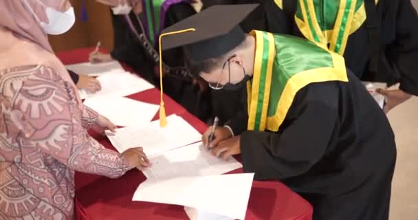 イベントが始まる前に卒業式でペン書きやサイン会を行う学生 — ストック動画