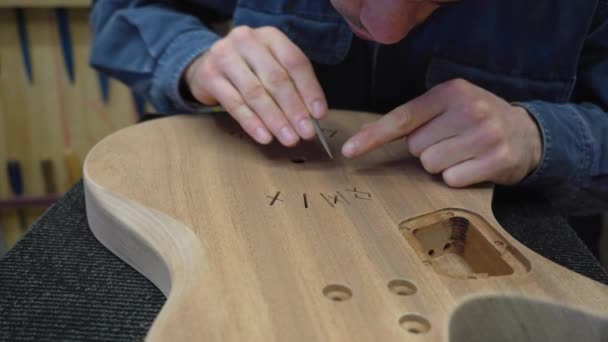 ギターの体の後ろにノルスのルーン彫刻を提出するルシファー プロの木工職人によるギターの装飾 — ストック動画