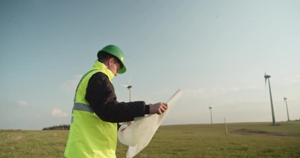 Yansıtıcı Yelek Giyen Bir Mühendis Rüzgar Çiftliğinde Tasarım Planlarıyla Duruyor — Stok video