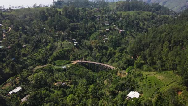 高い9アーチ橋は いくつかの観光客がスリランカの緑の自然の美しい景色を楽しむ2本の木で覆われた丘を接続しています ドローン ディッキー ティルトショット — ストック動画