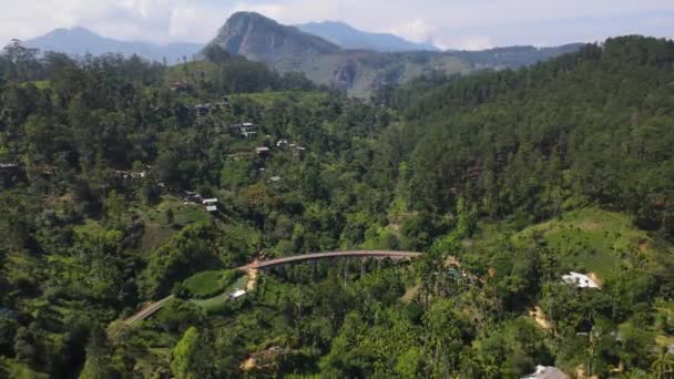 植民地時代からの美しい9つのアーチ鉄道橋は 晴れた日にスリランカの美しい自然の中で緑の森と高い山の間を巻きます ドローン ドーリーが撃たれた — ストック動画