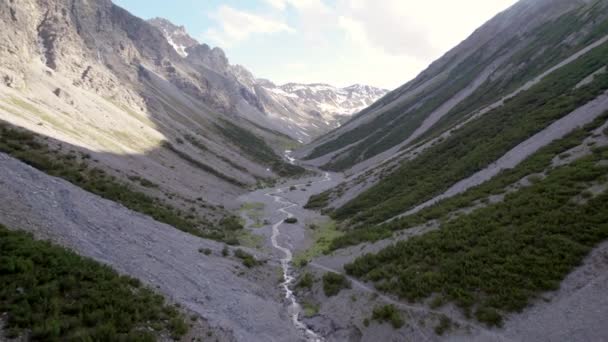 在瑞士 一架无人驾驶飞机在一个巨大的冰川山谷中飞驰而下 周围环绕着陡峭的高山和松树 还有几片白雪和一条高山小河 — 图库视频影像