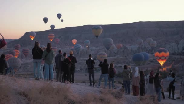 Άνθρωποι Παρακολουθούν Θεαματικά Αερόστατα Θερμού Αέρα Στην Καππαδοκία — Αρχείο Βίντεο