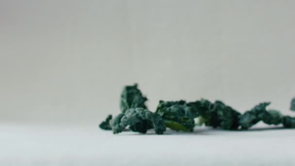 Pieces Green Kale Leaves Fall Slow Motion White Surface — Stock Video