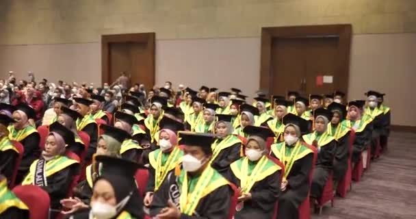 모자와 예복을 줄을서서 박수를 졸업생들 즐거운 대학교나 대학생들 졸업식을 즐기고 — 비디오