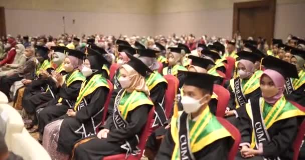 戴帽子 身穿长袍的快乐毕业生排成一排鼓掌 快乐的男女大学生在毕业典礼上玩得开心 有选择性地轻拍双手 — 图库视频影像
