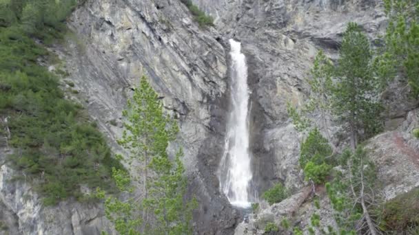 在瑞士 一架无人驾驶飞机在树冠上方缓缓飞行 从陡峭的山崖边缘滑向一个落水池 显示出巨大的瀑布 — 图库视频影像