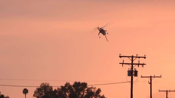 Požární Helikoptéře Přelétající Nad Elektrickým Vedením Během Zamlženého Západu Slunce — Stock video