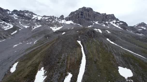 空中無人偵察機の映像をゆっくりと上方に劇的な ギザギザの山の風景を飛んで 雪の残りのパッチと印象的な灰色の岩の山のピークを探しています スイスのダボス近く — ストック動画