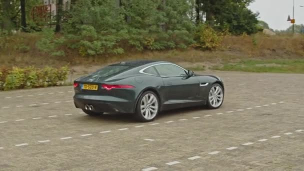 Grön Jaguar Type Sportbil Långsamt Lämnar Parkeringen Och Accelererar Snabbt — Stockvideo
