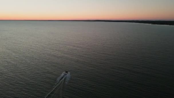 アメリカの海岸の日没時にオープンウォーターで航海中のボートのドローンショット — ストック動画