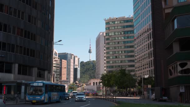 高層オフィスビルが立ち並ぶ都心通りからのNソウル南山タワーの眺めとソングロ道路での交通 — ストック動画