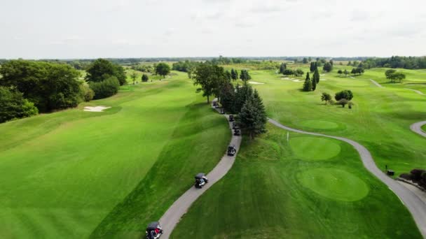 ゴルフ場を走るゴルフカートの空中ドローン撮影 — ストック動画