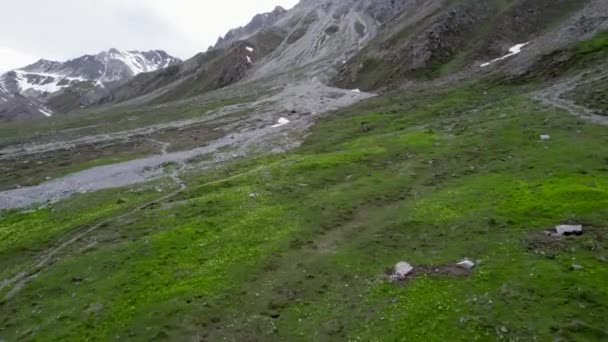 在瑞士 一架无人驾驶飞机在高山草原上空盘旋 然后在崎岖的冰封的山地景观中盘旋升腾 山中积雪斑斑 还有一条远足的小径 — 图库视频影像