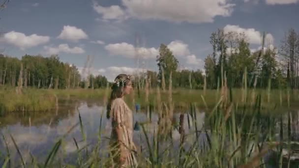 一个女人正在池塘边走着 这时摄像机正站在她后面 前面是高草 颜色渐变 动作缓慢 — 图库视频影像