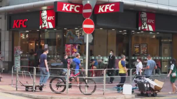 アジア人の歩行者がアメリカの多国籍ファストフードチェーン店ケンタッキー フライドチキン Kfc を通り 香港の賑やかな通りを歩いています — ストック動画