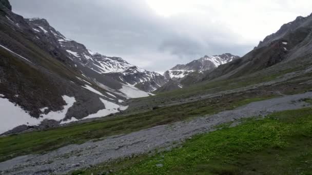 雪のパッチが施された氷河の山の風景の中を飛行する空中ドローン映像 人里離れた高山草原スイス — ストック動画