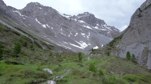 雪のパッチが施された氷河の山の風景を明らかにするためにまっすぐに上昇する空中ドローン映像 スイスの人里離れた高山ハイキングコース — ストック動画