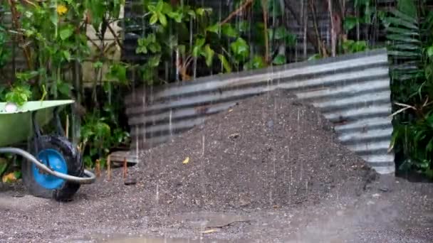 ぬれた雨の降水の間の建物の敷地内に灰色の砂利 板金及び緑色の車輪の山 — ストック動画