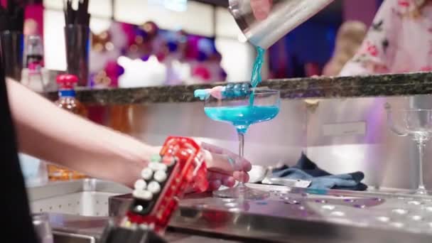 调酒师将蓝色混合鸡尾酒倒入酒吧后面装饰的玻璃杯中 慢动作4K — 图库视频影像
