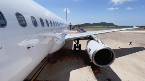 胴体翼の正面ドアからの眺めを上げ 晴れた日に階段が取り付けられたイビザバレアレス島空港に駐車した飛行機のエンジン スペイン — ストック動画
