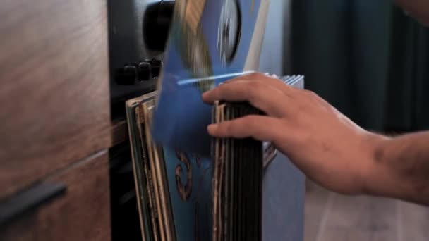 从家里的乙烯唱片系列中挑选唱片 检查车辙或质量 选择高质量的音乐在转盘上听 后面的扩音器男人的手靠得很近 — 图库视频影像