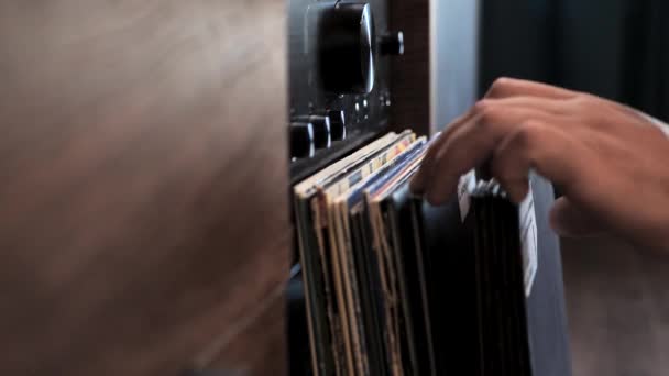 在听完音乐后 把一张乙烯唱片放回收藏品中 在家里选择高质量的音乐在转盘上听 后面的扩音器男人的手靠得很近 — 图库视频影像