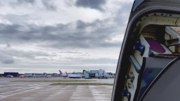 曇りの日にロンドン ガトウィック空港に駐機している航空機と飛行機のオープンドアの上の静かな眺め — ストック動画