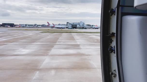 曇りの日にロンドン ガトウィック空港に駐機している航空機と飛行機のオープンドアの上の静かな眺め — ストック動画