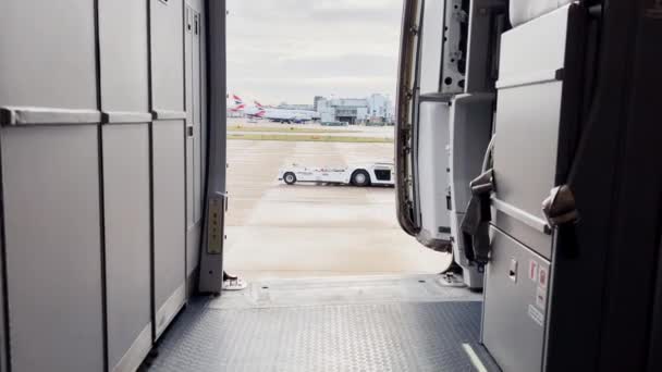 ロンドン ガトウィック空港に停車する航空機のドアが開いた飛行機内からの眺め曇りの日 — ストック動画