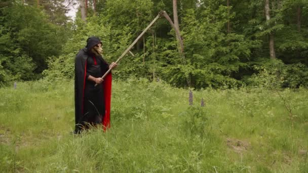 Schwarzer Sensenmann Mit Tierschädel Beim Versuch Wildblumen Mit Der Sense — Stockvideo