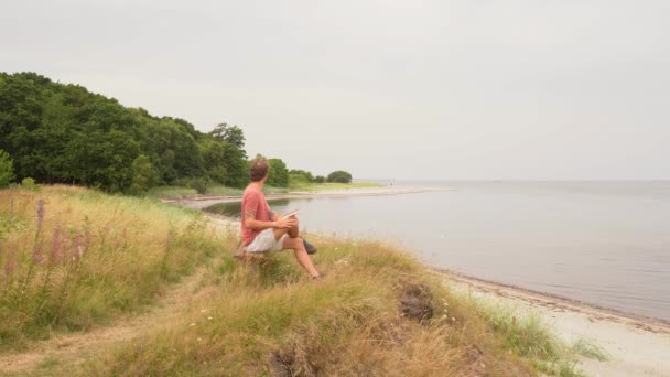 Man Reading Book Beach While Admiring Scenic Ocean Wide — Stock Video