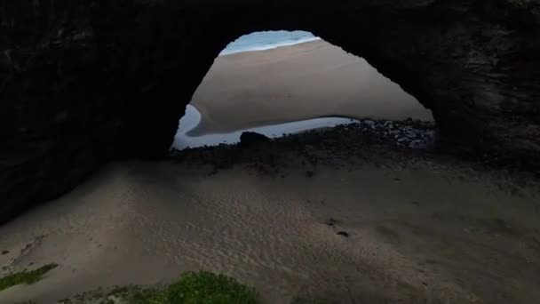 ハワイ州カウアイ島のナパリ海岸線の砂浜に向かって岩の中の天然の洞窟ランナーを飛ぶ — ストック動画