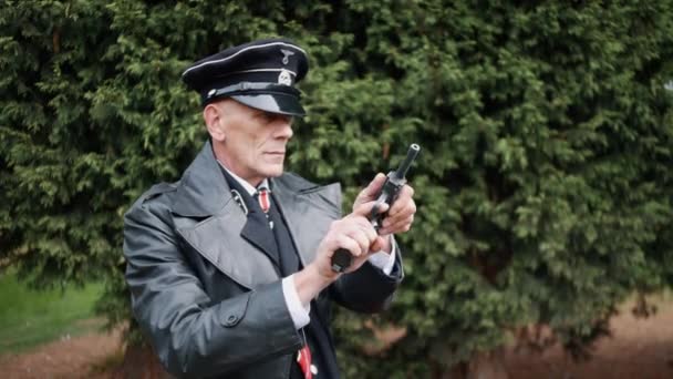 二战时期的德国纳粹军官身穿黑色制服 皮夹克 在树林里扭动着手枪 — 图库视频影像