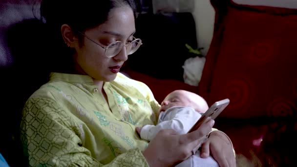 Young Asian Mother Checking Smartphone Holding Her Sleeping Newborn Son — Stock Video