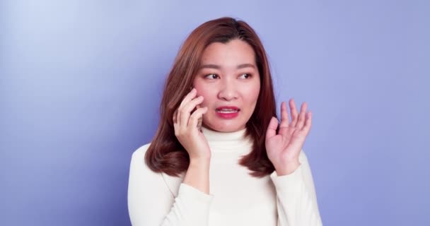 若いアジアの女性は 顧客とのネットワークにスマートフォン技術について話すか 紫色の背景に隔離された取引を交渉します — ストック動画