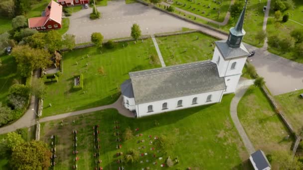 白い教会の上を塔と十字架で飛ぶ 墓石のある墓地 — ストック動画
