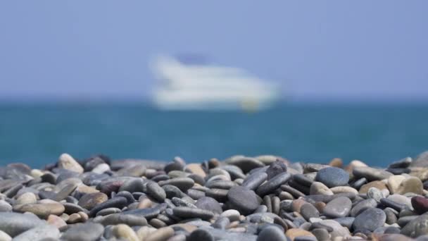 Kieselsteine Sonnigen Strand Mit Verschwommenem Schiff Auf See — Stockvideo