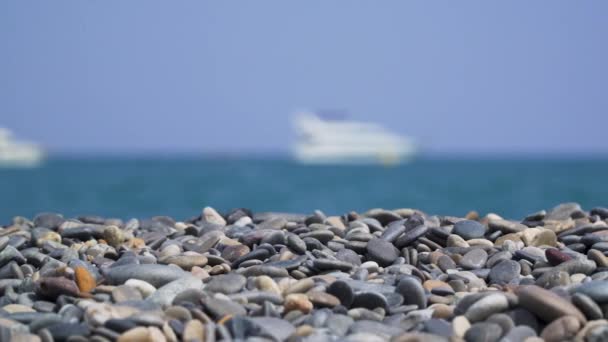 Kieselsteine Sonnigen Strand Mit Verschwommenem Schiff Auf See Schwenken Von — Stockvideo
