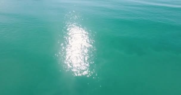 ニュージーランドの海岸線を明らかにするために傾いている豪華な青い海に反映されている太陽の空中ドローンショット — ストック動画